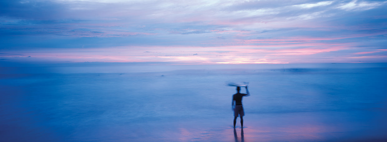 Silhouette of a man carrying a surfboard over his head on the beach, Costa Rica