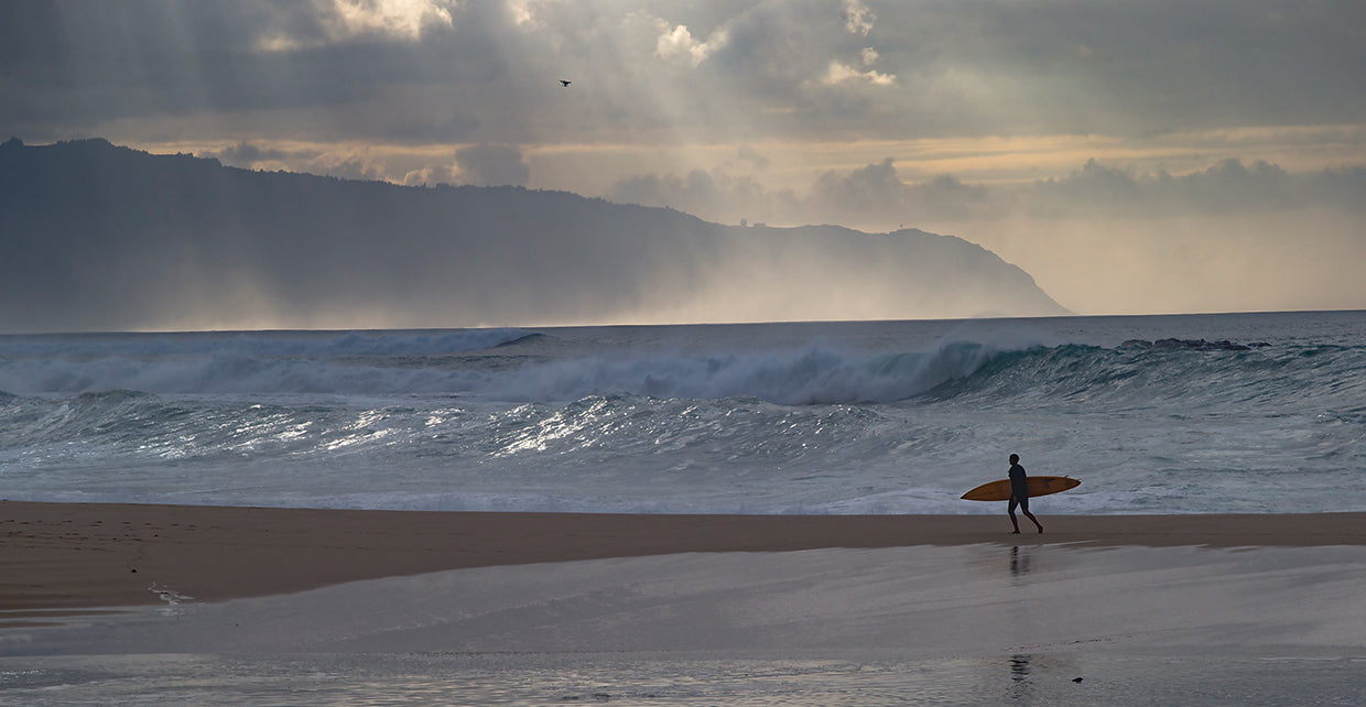 Surfer walking on the beach, Hawaii, USA