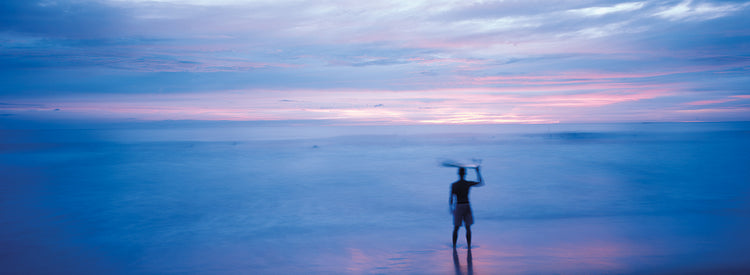 Silhouette of a man carrying a surfboard over his head on the beach, Costa Rica
