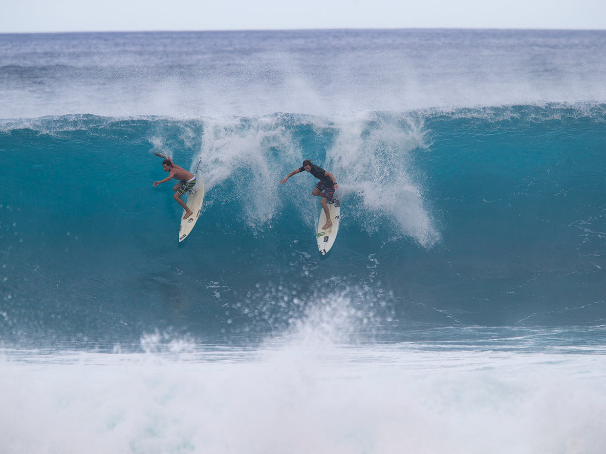 Surfers surfing down a wave on beach, Hawaii, USA