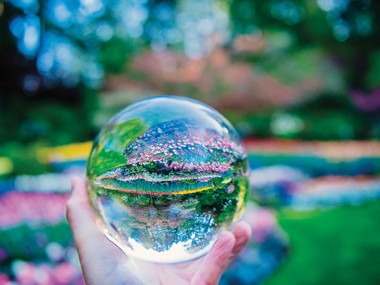 Hand holding crystal ball in formal garden, Butchart Gardens, Vancouver Island, British Columbia, Canada