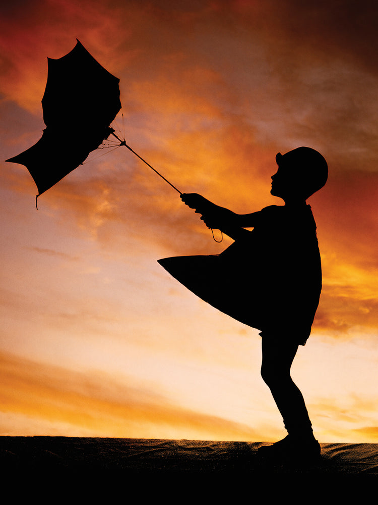 1920s ANONYMOUS SILHOUETTE OF LITTLE GIRL WITH UMBRELLA TURNED INSIDE OUT IN THE WIND COLORFUL SKY BACKGROUND